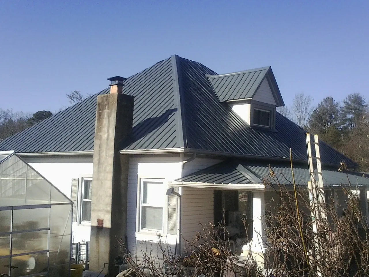 Dark blue standing seam metal roof on a white farmhouse with dormer — Slate & Tile Roof Repair by Roofing Brothers in Lynden