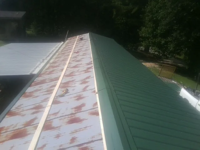 Old rusted panels beside newly installed green metal roofing — Wind Damage Roof Repair by Roofing Brothers in Lynden