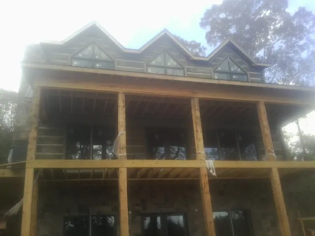 Dormers and porch framing on a large log home under construction — Roof Coating work by our crew in Lynden