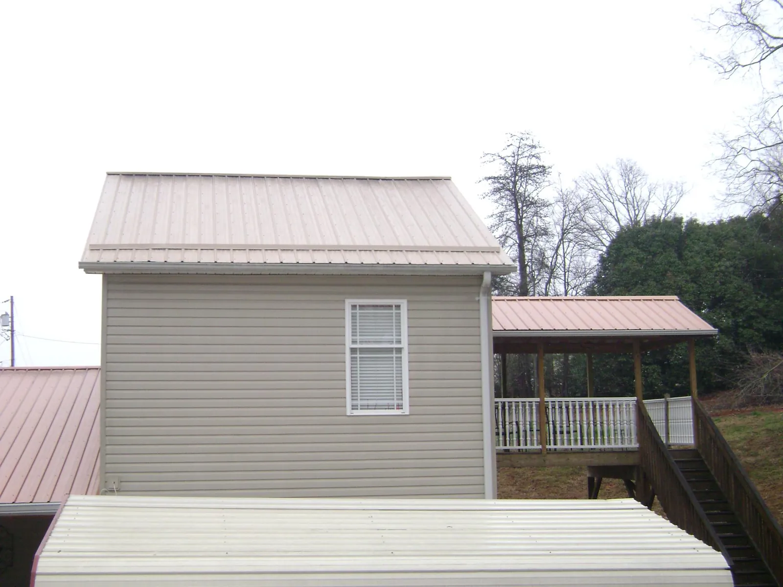 Tan metal roofs on a two story addition and attached porch, from a Roof Replacement job in Lynden