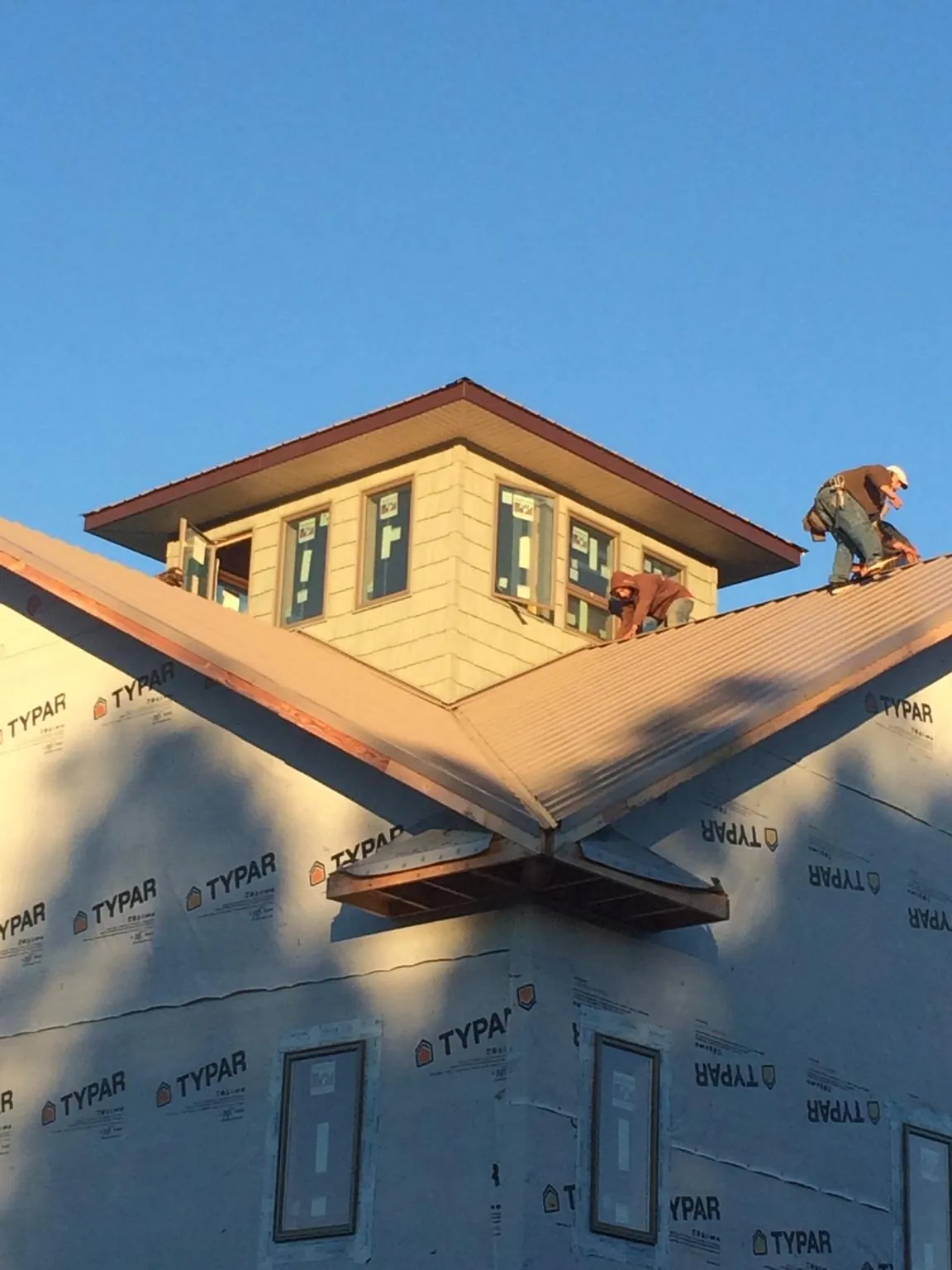 Roofers working around a rooftop cupola on a new metal roof at sunset — Roof Waterproofing in Lynden by Roofing Brothers
